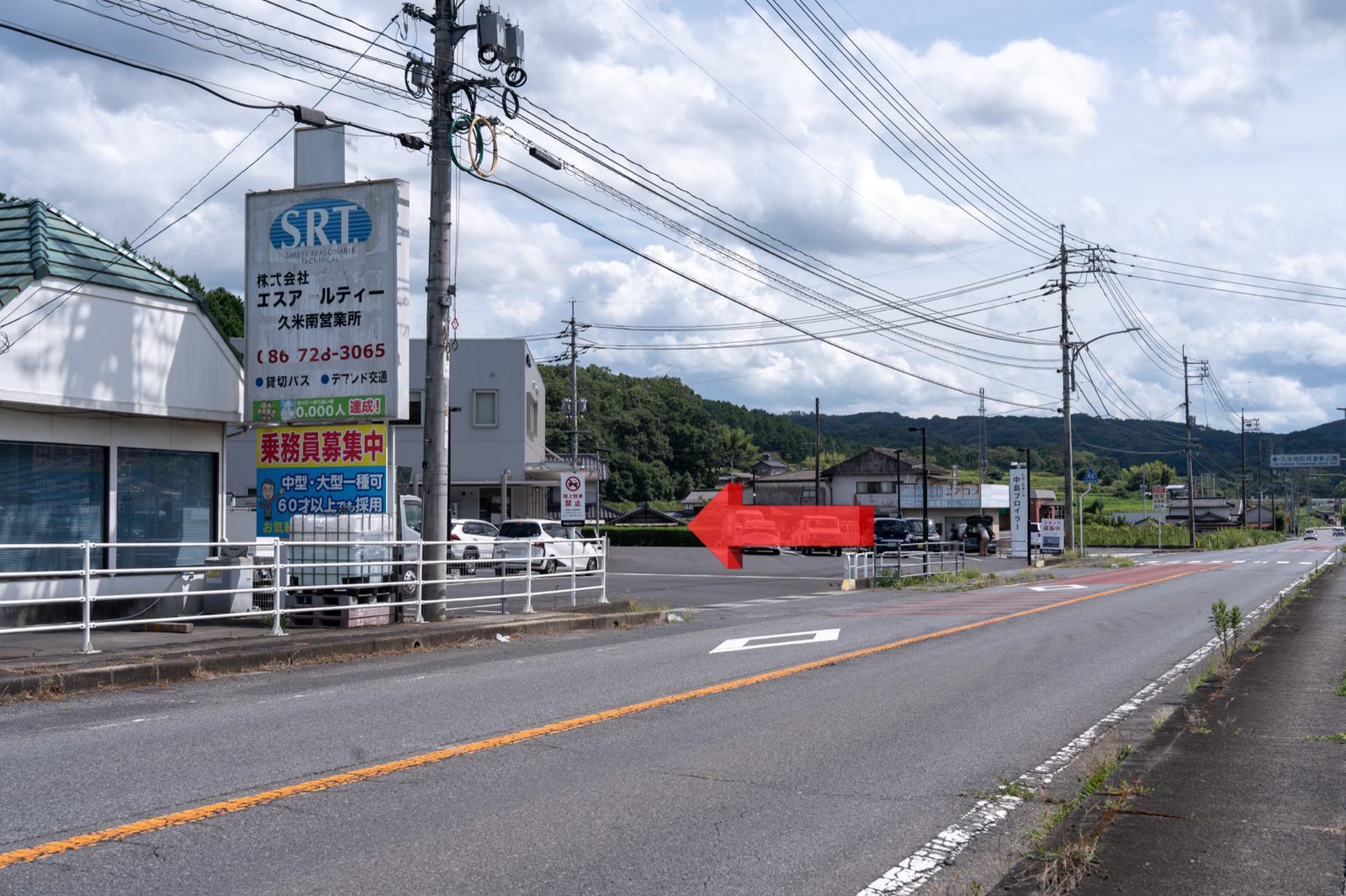 国道の北側から見た、砂利駐車場の北側出入り口（赤い矢印の位置）
